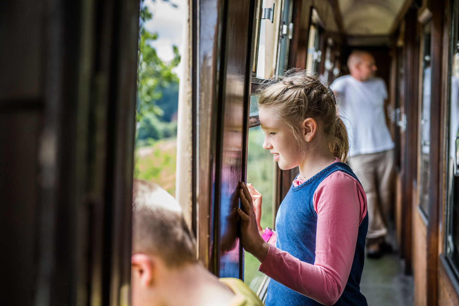 A young girl looks out the window of a heritage train coach